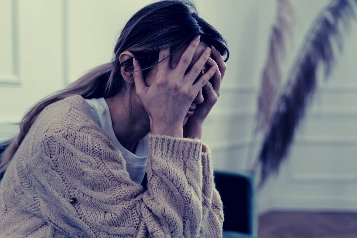 Woman Sitting with Hands Covering Her Face 